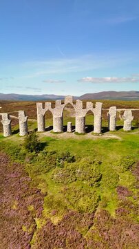 Cinematic Drone Aerial View of Fyrish Monument with Purple Heather in Bloom, Historic Stone Arches on Fyrish Hill Overlooking Cromarty Firth, Scottish Highlands Landscape, Evanton, Scotland, UK.