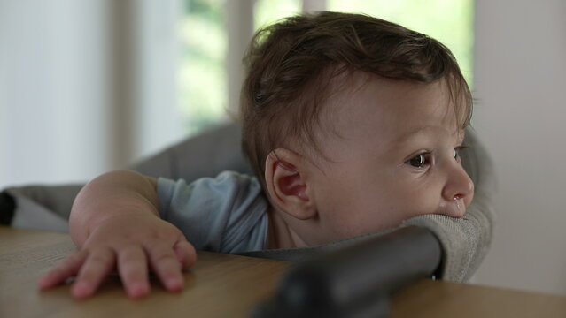 Baby biting high chair fabric, exploring texture with mouth, early teething behavior, curious infant interacting with surroundings, playful sensory discovery