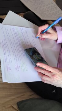 Woman using smartphone while writting on sofa