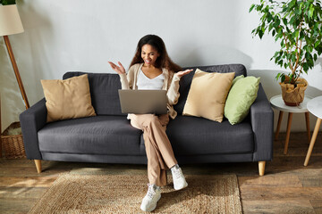 Obraz premium Young beautiful woman enjoys a cozy moment while working on her laptop in a stylish living room