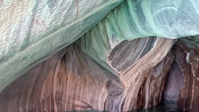 Discover the enchanting Marble Caves in Patagonia as soft light dances on the vibrant rocks. Observe the unique patterns and colors while gentle waves lap against these natural wonders.
