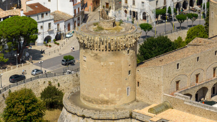 Close-up aerial view of a cylindrical tower, part of a medieval Italian fortress. The ancient fortification features ornate corbels and overlooks a historic town. It's located in Venosa, Basilicata. © Stefano Tammaro