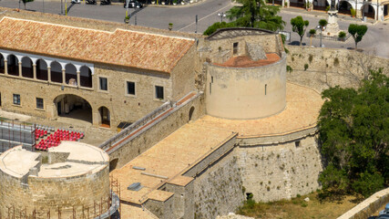 Close-up aerial view of a cylindrical tower, part of a medieval Italian fortress. The ancient fortification features ornate corbels and overlooks a historic town. It's located in Venosa, Basilicata. © Stefano Tammaro