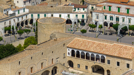 Close-up aerial view of a cylindrical tower, part of a medieval Italian fortress. The ancient fortification features ornate corbels and overlooks a historic town. It's located in Venosa, Basilicata. © Stefano Tammaro