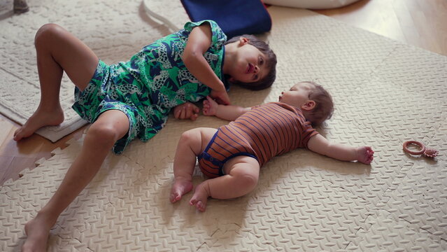 Young boy lying on mat beside baby, playful sibling interaction, joyful moment of bonding, childhood connection, love and laughter, affectionate family relationship