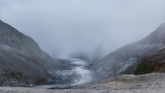 Glacier valley with steep rocky mountains and ice flowing through the center under a cloudy sky featuring landscape, nature, environment with cold
