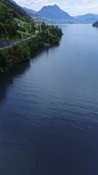 A picturesque lake nestled among the mountains in Switzerland. At the foot of mountains stretch lush green alpine meadows, dotted with charming houses. 