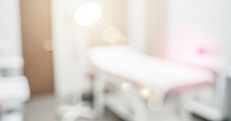 A blurred interior view of a modern treatment room featuring a treatment bed and ambient lighting, creating a serene and professional atmosphere suitable for skincare or wellness.