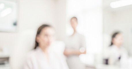 Fototapeta premium A soft-focused image depicting two women in a spa setting. One woman is seated, while another stands in the background, creating a serene atmosphere.