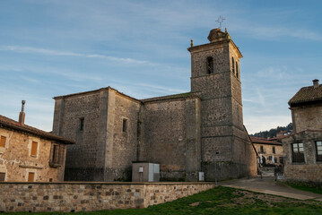 Obraz premium Exterior view of San Martín de Tours Church in Molinos de Duero, Soria, Spain, showing stone masonry walls and square bell tower, a historic rural church under a clear blue sky