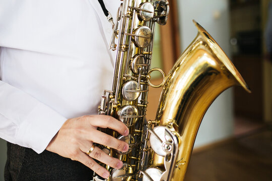 Man playing saxophone closeup during music performance. Brass sax instrument in musician hands. Jazz band rehearsal or concert practice concept with professional wind instrument detail.