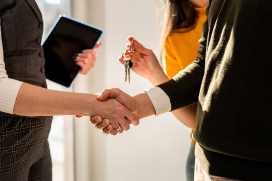 Close up of real estate agent handshake with her clients because of new apartment. 