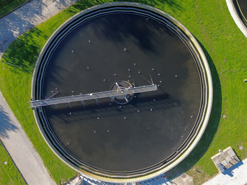 Wastewater treatment facility featuring a large circular clarifier surrounded by green landscaped areas. The plant showcases modern environmental purification processes designed to treat sewage effici