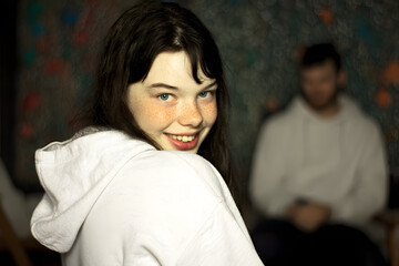 Fototapeta premium Smiling young girl with freckles in a cozy setting, warm colors and relaxed mood, focusing on her joyful expression.