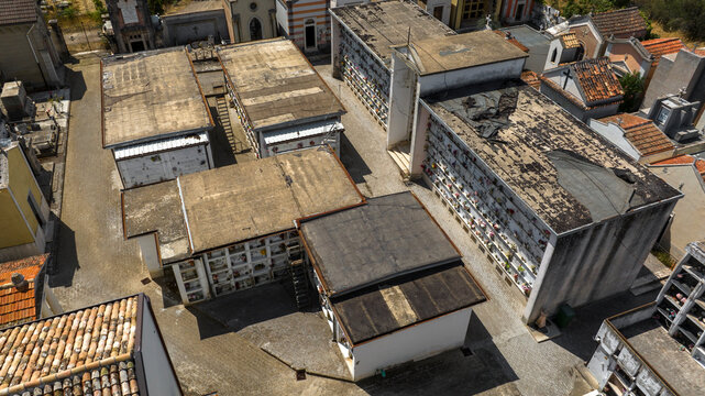 Aerial view of a Italian cemetery featuring rows of tombs and loculi. The architectural layout reflects solemn traditions, combining modern and historical burial structures in a quiet city of the dead