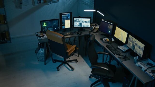 High angle view of dispatchers desk at police station with workplace equipped with multiple monitors showing CCTV footage, no people
