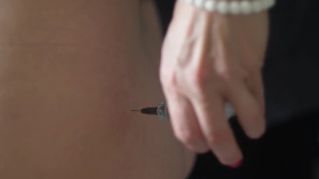 Close up of a medical needle being inserted into soft tissue. The process of performing an intramuscular injection with a syringe at home