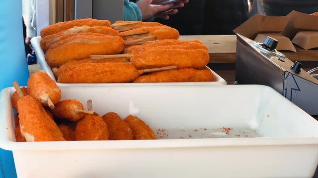 A crispy Corn Dog is freshly prepared at the street market. A juicy sausage on a stick is coated in thick batter and deep-fried to golden perfection.
