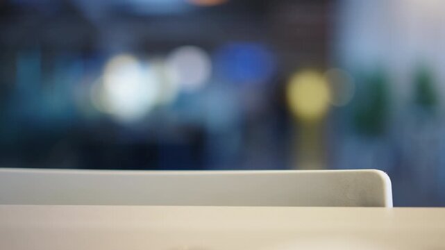 A clean, white surface in the foreground with a beautifully blurred background. Indistinct people walk by, creating a gentle sense of motion against soft, cool-toned bokeh lights