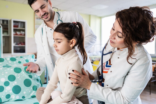 Two medical workers gently prepare a child for a vaccine, speaking softly to keep them calm. The moment feels careful and reassuring, focused on the child&rsquo;s comfort and safety.	
