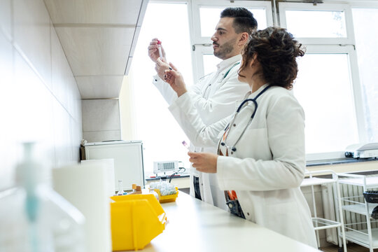 Two doctors prepare vaccines in a treatment lab, working carefully with medical equipment. The scene feels sterile and focused, highlighting precision and teamwork.	
