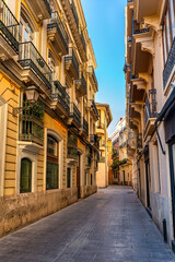 Naklejka premium Narrow street with old buildings in the center of the monumental city of Valencia, Spain.