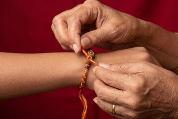 Hands tying traditional Rakhi thread on wrist in festival ritual