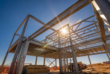 Steel frame construction of building under blue sky with sunburst