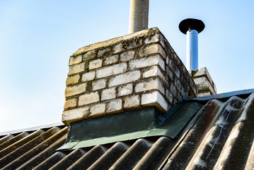 Naklejka premium Chimney pipe from stainless steel on the roof of the house. Repair of roof chimney, brickwork.