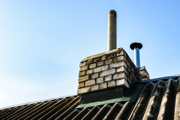 Naklejka premium Chimney pipe from stainless steel on the roof of the house. Repair of roof chimney, brickwork.
