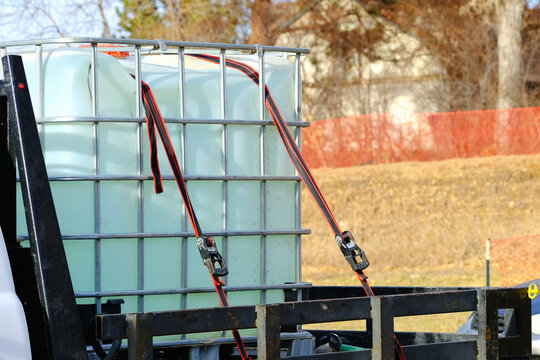 IBC water tank container on truck secured with ratchet straps.