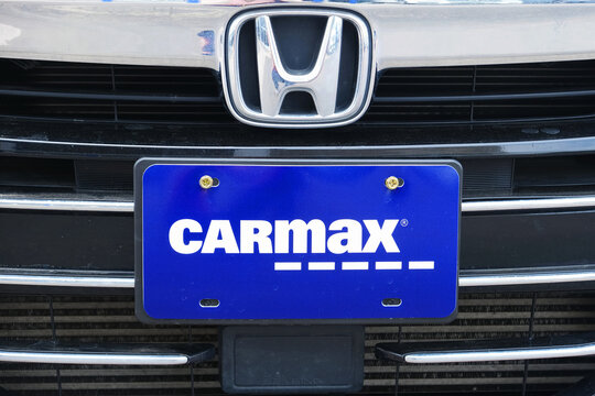 CarMax used car dealership license plate on a Honda car front grille closeup photo.