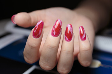 Red manicure with gel polish, beautiful female nails. Elegant red nails showcased with a hand positioned in a beauty setting during a salon appointment