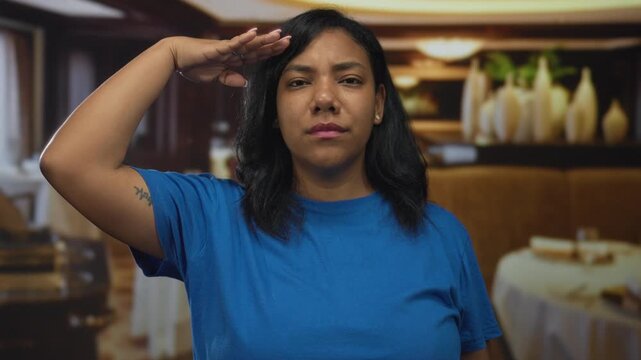 Woman salutes with hand to head in building before a row of ceramic vases and tables; respect duty honor.
