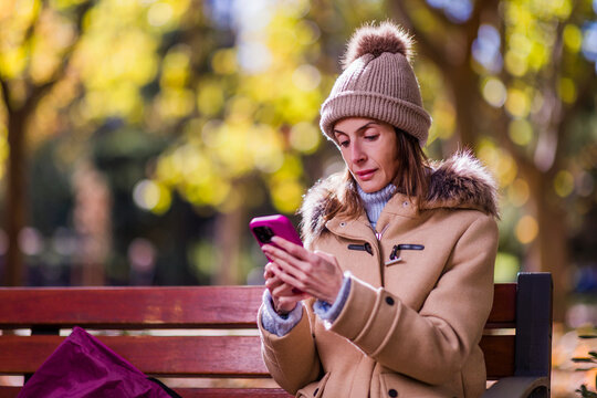 Woman with anorexia using phone in park during autumn