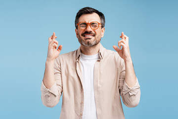 Naklejka premium Man crossing fingers, eyes closed, wishing for good luck and success