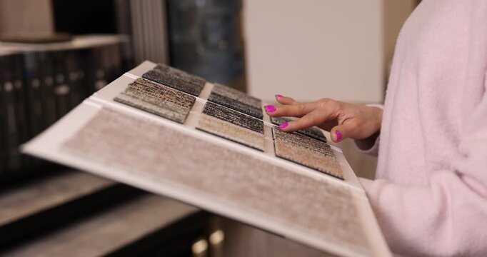 woman choosing carpet design from samples book in flooring shop