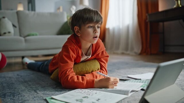 Schoolboy talking online lesson lying apartment floor looking tablet closeup. 