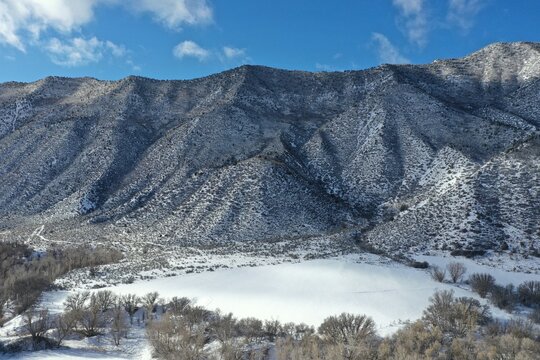 Aerial view of Grass Valley and Grand Hogback mountain ridge near New Castle, Colorado on sunny winter day after heavy snowfall.