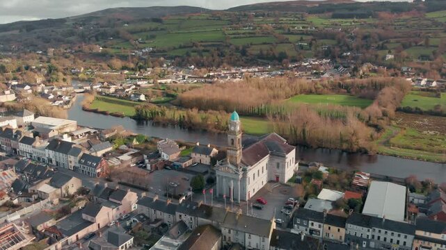 Aerial drone view gliding over historic St. Mary's Church and Clonmel town by the River Suir, Ireland, showcasing heritage and community.