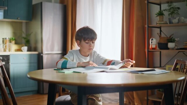 Smart child learning lesson doing homework at modern home kitchen closeup. 