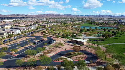 Obraz premium Stunning drone shot of the new Cadence master-planned neighborhood in Henderson. High-angle view of modern streets, intersections, and houses against the Nevada mountains and a cloudy blue sky.