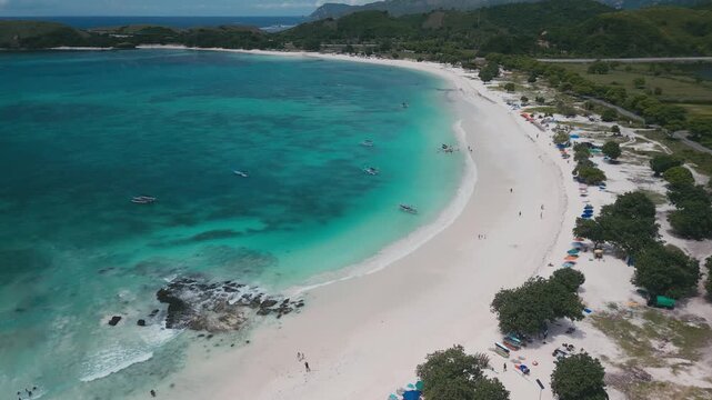 Small Boats Gather By White Sandy Beach. Fishing Boats And Charters Return Over Patterned Seabed. Aerial Perspective Of Vessels And Intricate Seafloor Designs Close To Pristine Beach, Lombok