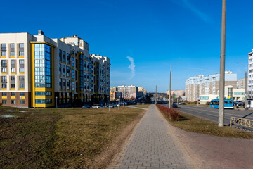 Modern residential apartment buildings and urban street with traffic signs and parked cars in contemporary city district under blue sky © Eugeniusz