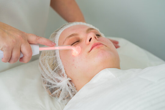 A client receives Darsonvalization treatment with a glass electrode that emits a warm glow, promoting healing and skin disinfection.