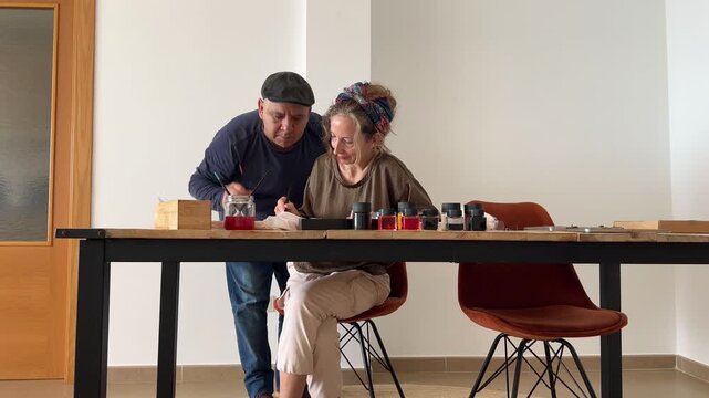 Profesor supervisando y explicando a alumna en taller de pintura en seda