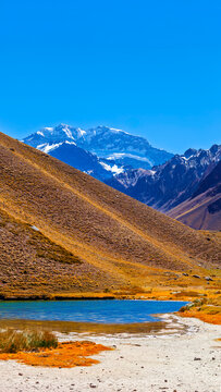 Uma paisagem de alta altitude com o pico nevado do Monte Aconc&aacute;gua, a montanha mais alta das Am&eacute;ricas, elevando-se acima da &aacute;rida cordilheira dos Andes.