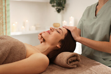 Beautiful woman receiving facial massage on couch in salon, closeup