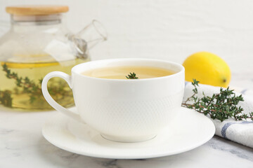 Fototapeta premium Fresh thyme tea in cup on white marble table, closeup