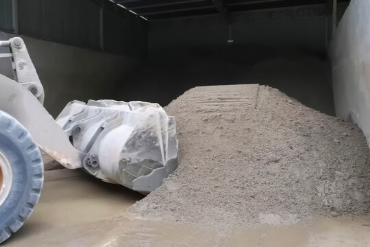 Bulldozer with bucket scooping sand from construction base stora